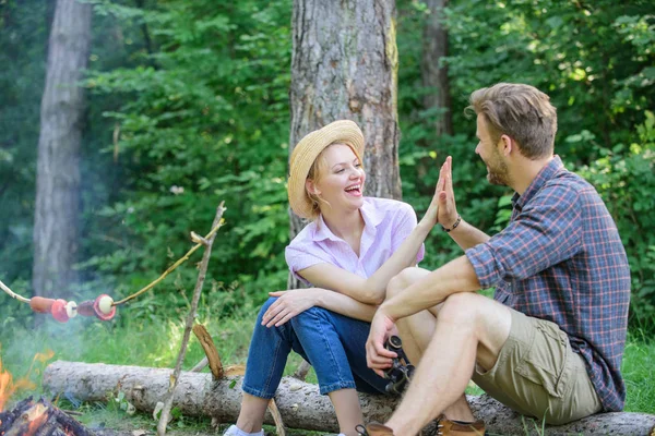 Couple tourists throwing their gesture while sit log bonfire. Man and girl play hand gesture game. Couple play hand game. Hand gesture game decide who win. Play while wait roasting food. High five