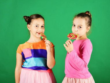 Yuvarlak, uzun şekilli lolipopları olan kız kardeşler. Mutlu yüzlü kızlar.