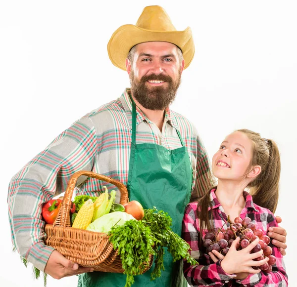 Man bearded rustic farmer with kid. Farmers family homegrown harvest. Father farmer or gardener with daughter hold basket harvest vegetables. Gardening and harvesting. Family farm organic vegetables