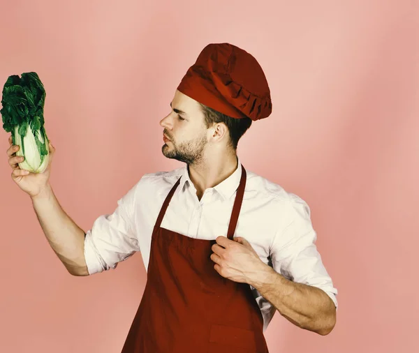 Vegetarisches Essen. Koch mit neugierigem Gesicht hält Salatbüschel in der Hand — Stockfoto