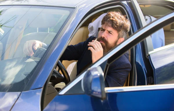 Hombre barbudo hombre de negocios fumando cigarrillo mientras se sienta en el coche. Conductor fumando cigarrillo. Un minuto para relajarse. Empresario cansado después de duras negociaciones de fumar vehículo. Prohibiciones de fumar en vehículos privados — Foto de Stock