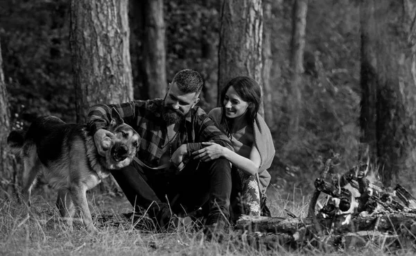 Couple with german shepherd dog near bonfire,