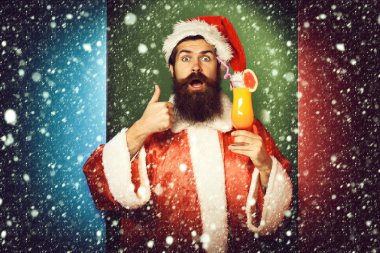 Noel veya xmas kazak ve renkli stüdyo arka plan üzerinde serin gösterilen yeni yıl şapkası alkolsüz kokteyl bardak tutan sürpriz yüzünde uzun sakallı yakışıklı Noel Baba adam sakallı