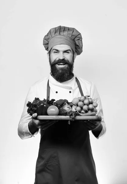 シェフは新鮮な野菜でボードを提供しています。髭を生やした男 — ストック写真
