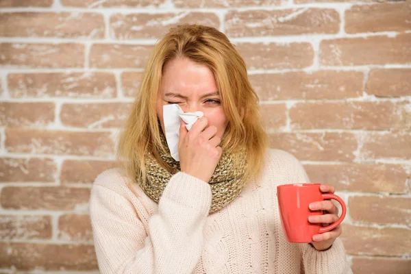 Средства должны помочь победить холод быстро. Советы, как избавиться от простуды. Женщина плохо чихает. Девушка в шарфе держит чайную кружку и салфетку. Насморк и другие симптомы простуды. Средства от простуды и гриппа — стоковое фото