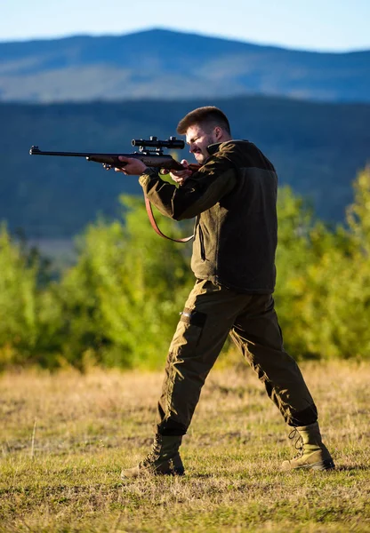 Man rifle for hunt. Hunter khaki clothes ready to hunt hold gun mountains background. Hunter with rifle looking for animal. Hunting shooting trophy. Mental preparation for hunting individual process