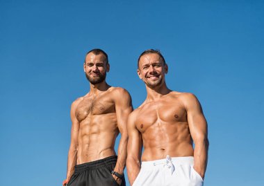 Erkekler kas vücut güvenle ile poz ceplerinde eller. Spor ve welness. Kaslı erkek çocuklar rahat görünüyor. Erkekler seksi kaslı çıplak gövde stand açık. Sporcular kas göbek poz