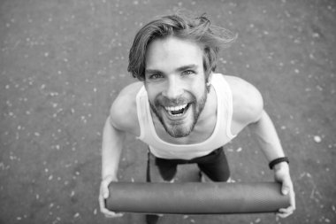 Vücudunuzun germek. Sporcu açık pratik için yoga mat taşır. Açık yoga kavramı. Her zaman germe egzersiz yaptıktan sonra atlet. Dostum atlet neşeli yüzü mat, germe için gidiş taşır