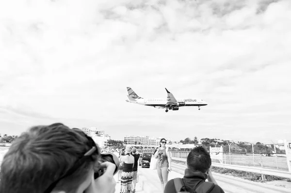 Philipsburg, San Martín - 24 de enero de 2016: vacaciones en la playa del maho en el Caribe. Avión de vuelo bajo sobre la gente. Vuelo en avión aterriza en el cielo nublado. Avión en nubes soleadas. Wanderlust, viaje y viaje — Foto de Stock