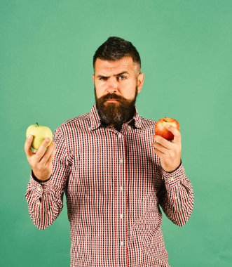 Sakallı adam kırmızı ve yeşil elma tutuyor.