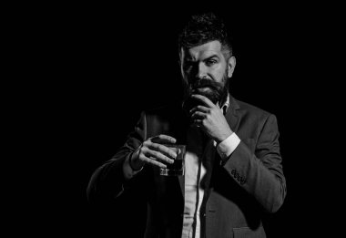 Siyah arka planda sakalı ve içeceği olan bir iş adamı.