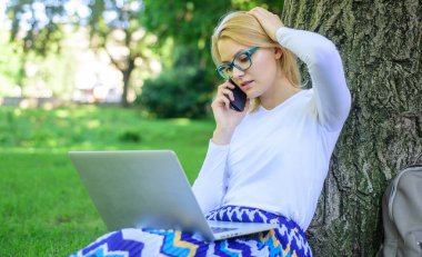 Girl takes advantage of online shopping. Save your time with shopping online. Sales manager occupation benefits. Girl sit grass with notebook. Woman with laptop in park order item on phone clipart