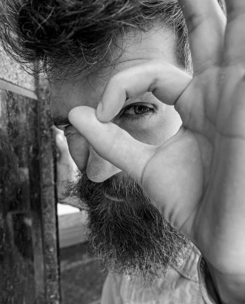 Watching concept. Guy looks suspicious through ok gesture, close up. Hipster with tousled hair looking, observing, watching. Man with beard on thoughtful, suspicious face, black marble background — Stock Photo, Image