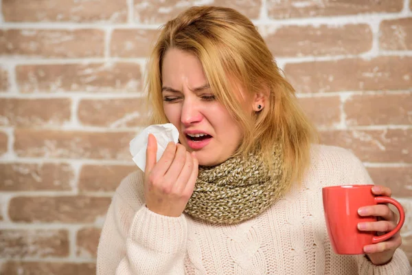 Девушка в шарфе держит чайную кружку и салфетку. Средства от простуды и гриппа. Насморк и другие симптомы простуды. Средства должны помочь победить холод быстро. Советы, как избавиться от простуды. Женщина плохо чихает. — стоковое фото