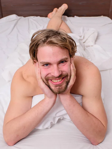 Man feel full of energy after pleasant night dream. Playful mood concept. Guy sexy macho lay white bedclothes. Pleasant relax concept. Man unshaven handsome happy smiling torso relaxing bed