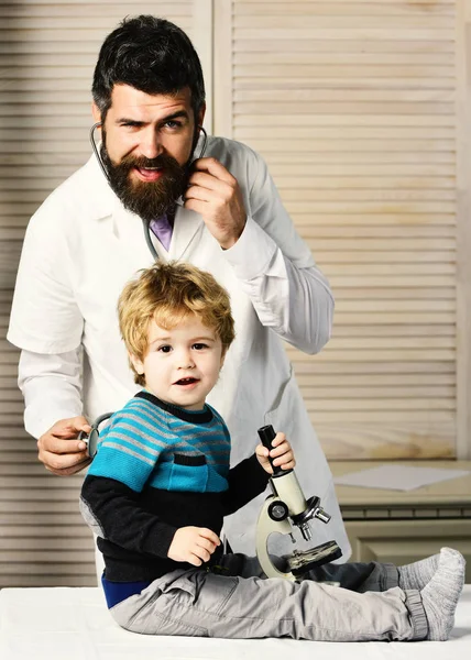 Pediatr a malý asistent hrát s mikroskopem — Stock fotografie