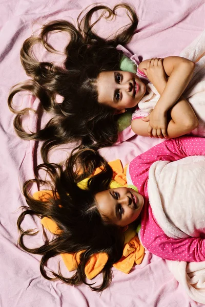 Childhood and love concept. Girls on white and pink sheets