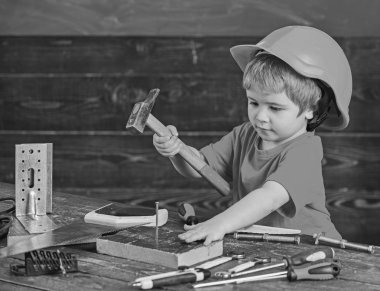 Yürümeye başlayan çocuk meşgul yüzündeki çekiç aracı evde atölye ile oynuyor. Çocuk Çocuk tamirci oynamak. Kask Oluşturucu veya repairer, onarımı veya handcrafting olarak oynayan sevimli çocuk. Handcrafting kavramı
