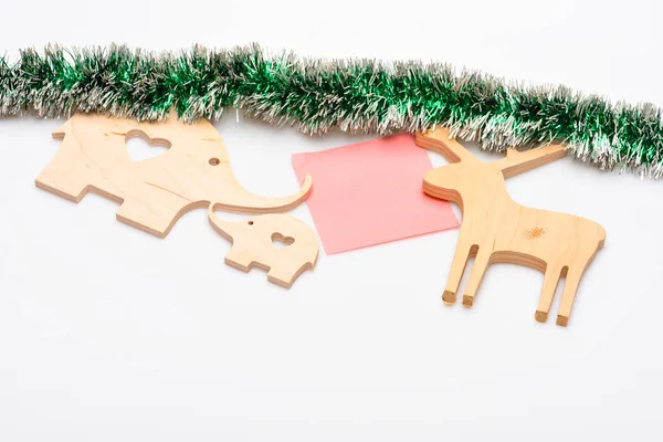 Decoraciones para las vacaciones de Navidad hechas de materiales naturales y oropel. Juguetes de madera de ciervo y elefante o decoración con papel para anotar sobre fondo blanco. Decoraciones de Navidad concepto —  Fotos de Stock