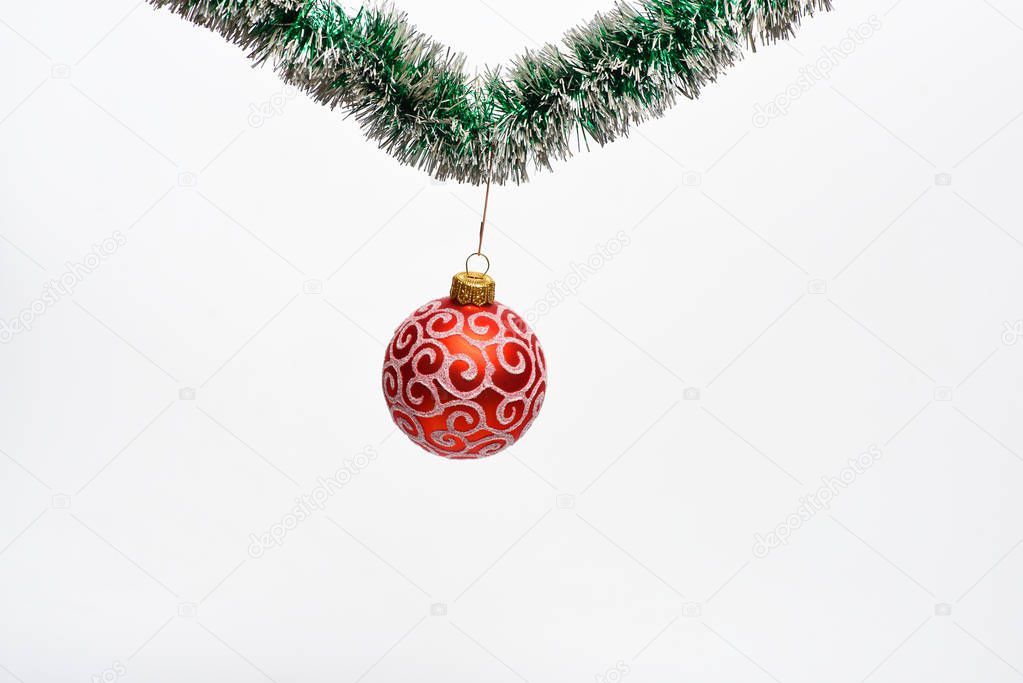 Christmas ornament concept. Decoration for Christmas tree hang on tinsel. Tinsel with pinned christmas toy, white background, copy space. Ball with glamorous ornaments hang on shimmering green tinsel