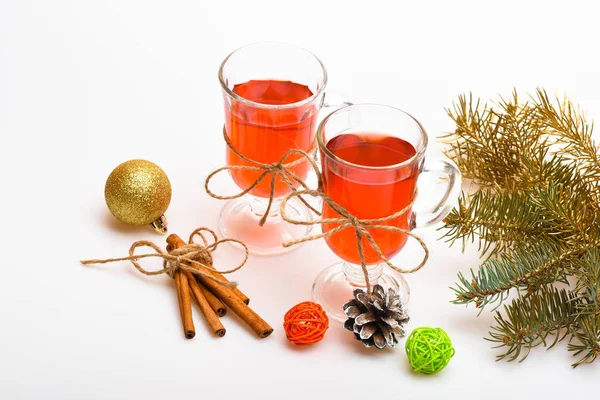 Glasses with mulled wine or cider tied with twine, white background. Traditional mulled wine with spices near fir branch. Mulled wine or hot beverage and cinnamon sticks. Winter drinks concept