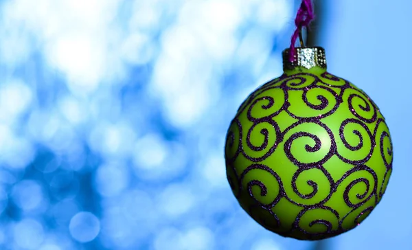 Decoração festiva para árvore de Natal, bola verde com decoração de brilho no fundo embaçado azul. Decoração de Natal ou brinquedo para árvore de Natal com detalhes cintilantes, espaço de cópia. Conceito de ornamento — Fotografia de Stock