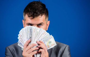 Kolay nakit krediler. İşadamı nakit para var. Zenginlik ve refah kavramı. Nakit para kolay ve hızlı bir şekilde almak. Para gibi kokuyor. Resmi takım elbise tutun doları banknot yığını mavi arka plan.