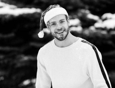 Kışın açık havada Noel Baba şapkalı yakışıklı bir adam.