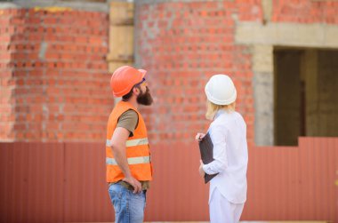 İnşaat endüstri kavramı. Kadın mühendis ve sakallı acımasız builder İnşaat ilerleme tartışmak. İnşaat Proje yönetimi. Bina endüstriyel proje. İlerleme projeyi tartışmak