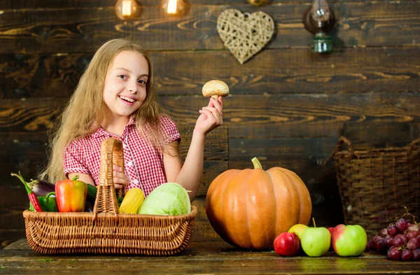 Oogstfeest concept. Kind meisje oogst van haar moestuin op houten achtergrond presenteren. Jongen meisje besteden jeugd boerderij. Mand vol verse groenten oogsten. Verzamelen oogst tradities — Stockfoto