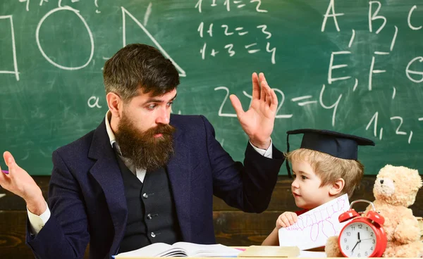 小学校のコンセプトです。先生は、鏝板、背景に黒板の生徒。父は息子を教えて基礎知識について、説明します。先生、注意する聞くと子供研究 — ストック写真