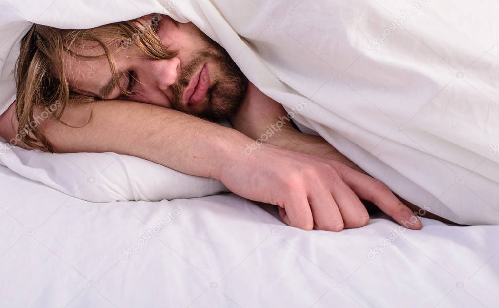 Man sleepy drowsy unshaven bearded face covered with blanket having rest. Guy lay under white bedclothes. Fresh bedclothes concept. Man unshaven handsome relaxing bed. Let your body feel comfortable