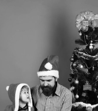 Sakallı ve çocuklu baba Noel ağacının yanında konuşuyor..