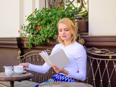 Bir fincan kahve iyi ve keyifli kitap en iyi kombinasyonu mükemmel hafta sonu için. Kız içki kahve her sabah saat aynı yerde günlük ritüel. Kadın açık havada içki kafe teras vardır. Kitap kurdu eğlence kavramı