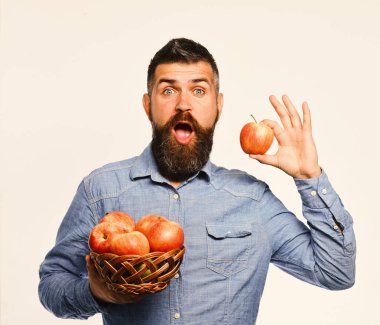 Şaşırmış suratlı çiftçi kırmızı elma tutuyor.