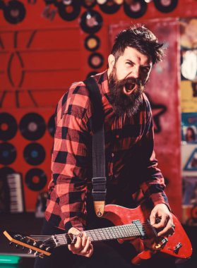 Hevesli yüzü olan bir adam gitar tutar, şarkı söyler, müzik çalar.,