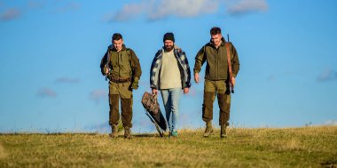 Avcılar silahlı güneşli sonbahar gün yürür, yürür. Acımasız hobi. Grup erkek avcılar veya gamekeepers doğa arka plan mavi gökyüzü. Çocuklar için avcılık toplandı. Erkek av tüfekleri taşırlar. Hobi ve eğlence avcılık