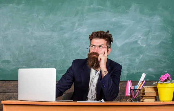 Soy tu nueva maestra. Profesora de escuela lista para empezar la lección. Profesor sentarse en el escritorio con el ordenador portátil. De vuelta al concepto escolar. Maestro barbudo hipster con anteojos sentarse en el aula pizarra fondo —  Fotos de Stock