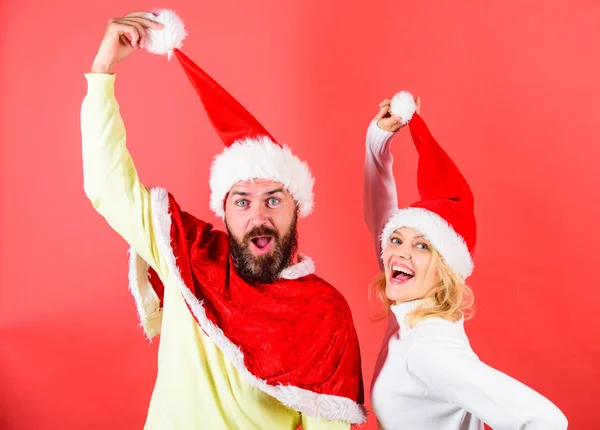 Couple célébrer Noël vacances d'hiver fête. Mascarade de Noël ou concept de carnaval. Homme avec barbe et femme en chapeau de Père Noël avec fond rouge pompon. Couple visage joyeux célébrer Noël — Photo