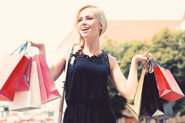 Senhora com cabelo loiro e rosto sorridente detém sacos de compras . — Fotografia de Stock