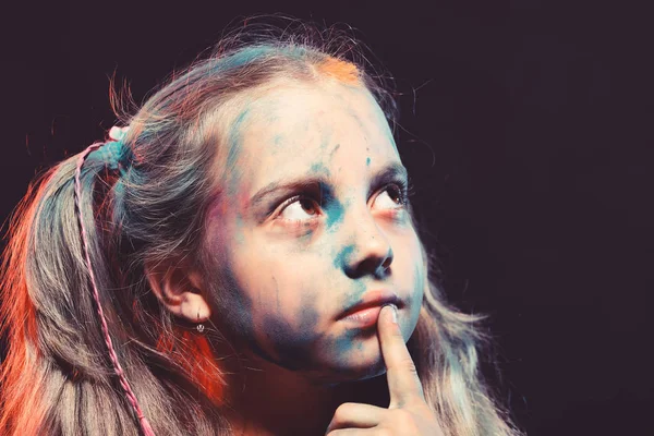 Schoolgirl has paint spots on face. Children and creativity