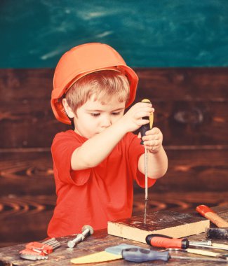 Çocuk Çocuk Tornavida Aracı tutar. Yürümeye başlayan çocuk meşgul yüzündeki tornavida ile Atölyesi'nde oynamaktadır. Kask Oluşturucu veya repairer, veya handcrafting şirin çocuk. Handcrafting ve atölye kavramı