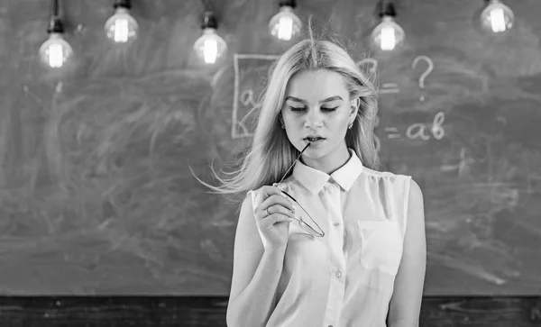 Conceito de professor sexy. Mulher com cabelos longos em blusa branca fica na sala de aula. Senhora professora estrita no rosto sonhador fica na frente de quadro-negro. Professor com óculos e acenando cabelo parece sexy — Fotografia de Stock