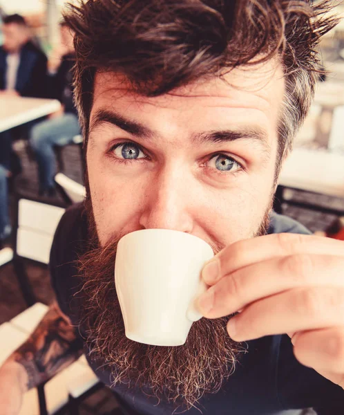 Парень отдыхает с кофе эспрессо. Концепция кофе-брейка Хипстер на спокойном лице пьет кофе на открытом воздухе, закрывается. Человек с бородой и усами держит чашку кофе, расслабляясь на террасе кафе — стоковое фото