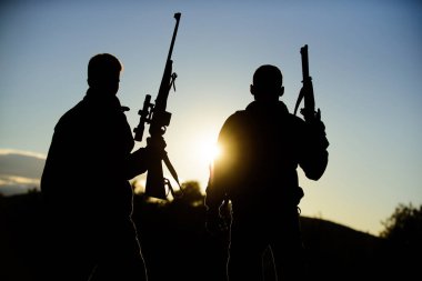 Avcılık ortağı ile daha büyük ölçü Emanet eğlenceli ve ödüllendirici sağlar. Avcılar arkadaşlar gamekeepers silahlı gökyüzü arka plan siluet. Avcı tüfekler doğa ortamı. Avcı arkadaş zevk eğlence