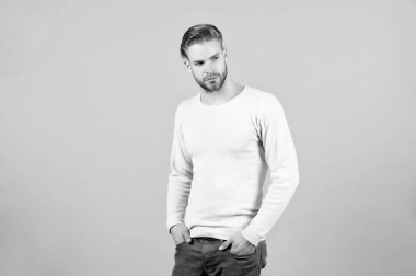 Sakal tıraşsız adam olan adam yakışıklı görünüyor ve rahat kıyafetler de bakımlı. Adam sakallı ve saç modeli ile çekici. Erkeklik kavramı. Sakallı sıkı konsantre face, gri arka planı olan adam