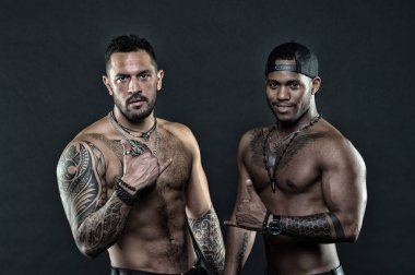 Afrika İspanyol erkekler seksi çıplak gövde. Erkek dövmeli vücut uygun. Dövmeli manken shaka hareketini göster. Seksi çocuklar koyu arka plan asmak. Samimi niyet asmak gevşek jesti bilinen Shaka işareti