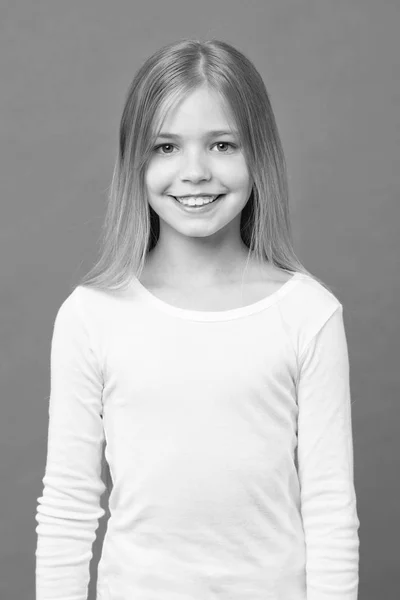 Ragazza sul viso sorridente con i capelli lunghi indossa camicia bianca, sfondo viola. Ragazza con i capelli lunghi sembra adorabile. Acconciatura e concetto di cura dei capelli. Ragazza ama guardare carino, elegante e alla moda — Foto Stock