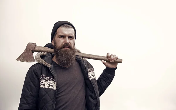 Barbudo guapo hombre serio con hacha oxidada contra el cielo nublado — Foto de Stock