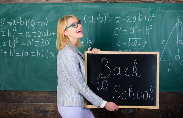 Professeur heureux d'accueillir les élèves. Super début d'année scolaire. Meilleures façons d'accueillir les élèves à l'école. La maîtresse garde l'inscription au tableau noir à l'école. C'est l'heure de l'école agai — Photo